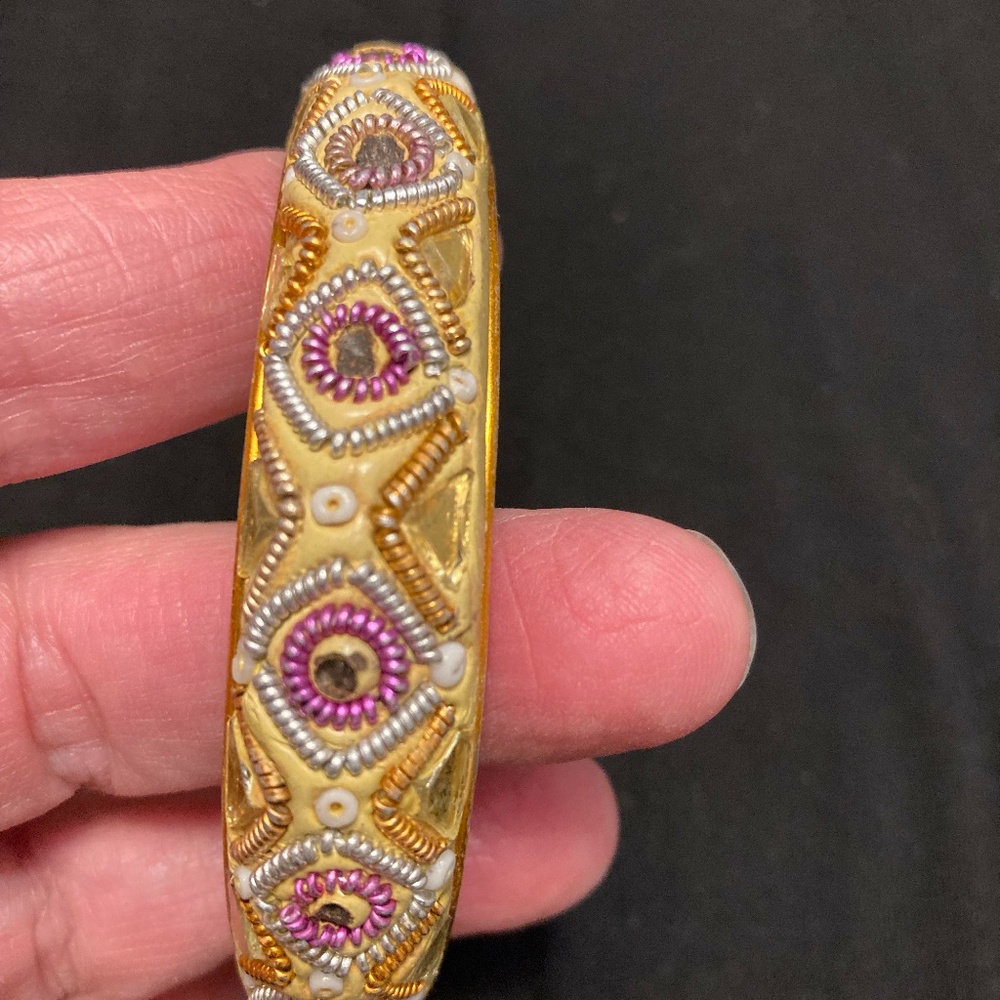 Gold bangle bracelet with purple and silver decorations with rectangle mirrors.